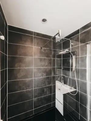 a bathroom with a black tiled wall at Hotel Zand in Zandvoort