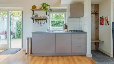 a kitchen with white cabinets and a window at Molenzicht in Sint Maarten