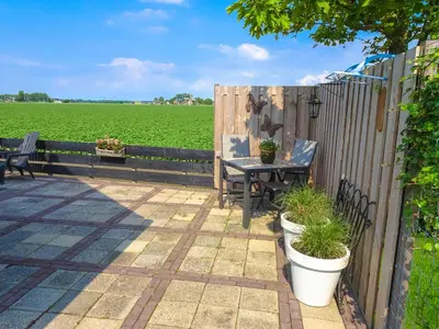 a patio with a table and a fence and a field at Molenzicht in Sint Maarten