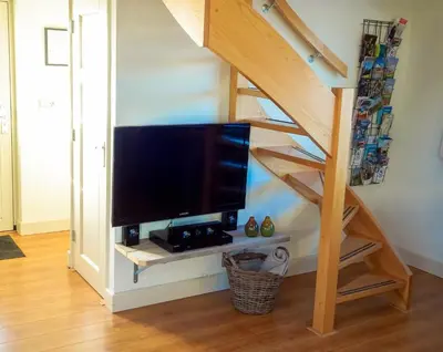 a living room with a tv under a staircase at Molenzicht in Sint Maarten