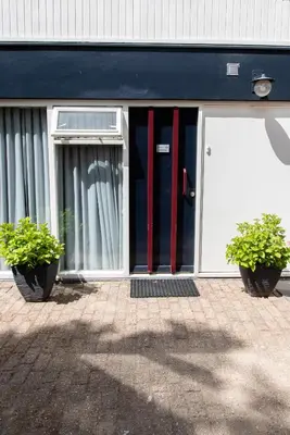 two potted plants in front of a building with a door at Excellent 21 in Soesterberg