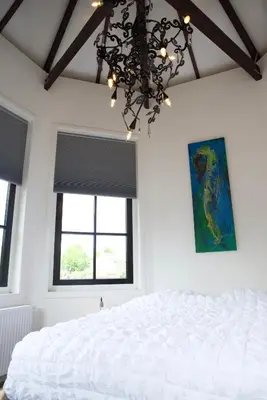 a bedroom with a white bed and a chandelier at Het Torentje aan de IJssel in Montfoort