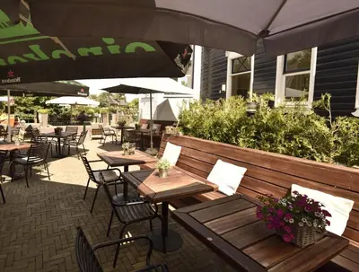 an outdoor patio with tables and chairs and umbrellas at Het Torentje aan de IJssel in Montfoort