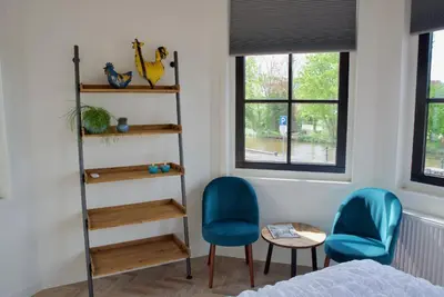 a bedroom with two blue chairs and a book shelf at Het Torentje aan de IJssel in Montfoort