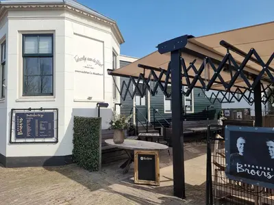 a pavilion with a picnic table in front of a building at Het Torentje aan de IJssel in Montfoort