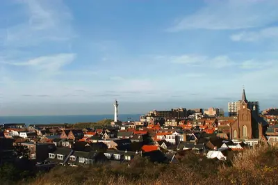 a view of a city with a lighthouse in the background at Duinnachtegaal in Egmond aan Zee