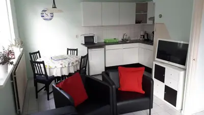 a kitchen with a living room with a table and chairs at Duinnachtegaal in Egmond aan Zee