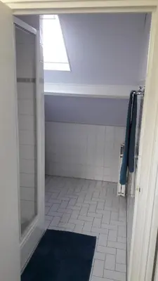 a bathroom with a shower and a blue rug at Duinnachtegaal in Egmond aan Zee
