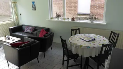 a living room with a table and chairs and a couch at Duinnachtegaal in Egmond aan Zee