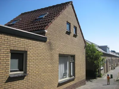 a brick building with two windows on a street at Duinnachtegaal in Egmond aan Zee