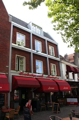 a woman standing in front of a brick building at Hotel Keistad in Amersfoort