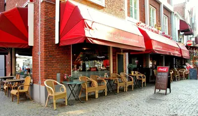 a restaurant with tables and chairs and red umbrellas at Hotel Keistad in Amersfoort