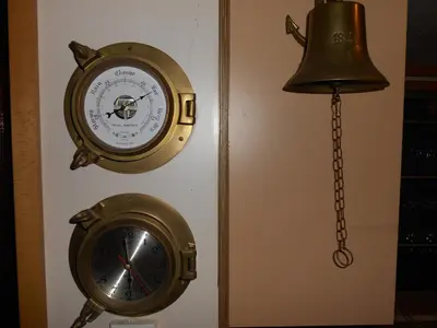 a clock and a bell hanging on a wall at Hotelboat Iris in Amsterdam