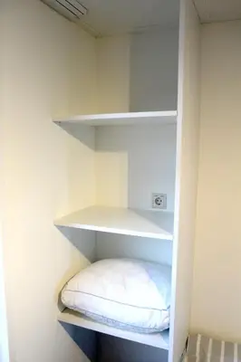 a small closet with white shelves and a pillow at Houseboat Linquenda in Woubrugge