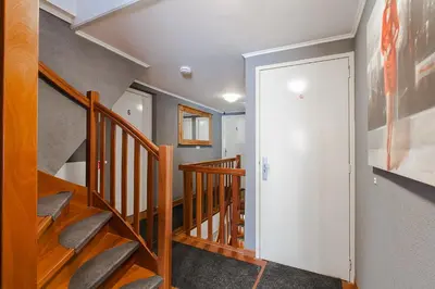 a hallway with wooden stairs and a white door at Alex Rooms in Zwanenburg