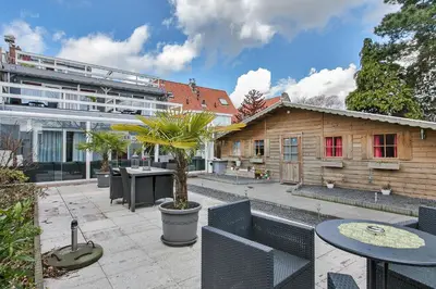 a patio with tables and chairs and a building at Alex Rooms in Zwanenburg