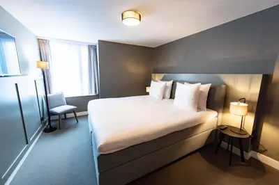 a hotel room with a large bed and a chair at Boutique Hotel Zaan in Zaandijk
