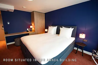 a bedroom with a large bed with blue walls at Boutique Hotel Zaan in Zaandijk
