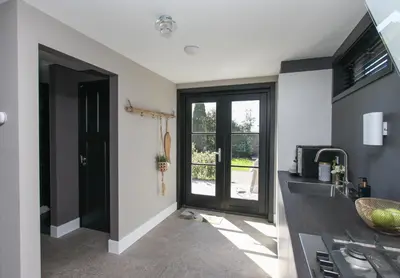 a kitchen with a sink and a door with a window at Chill-out in Nieuwe Wetering