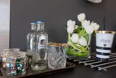 a tray with bottles and glasses and flowers on a table at Chill-out in Nieuwe Wetering