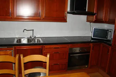 a kitchen with wooden cabinets and a sink and a microwave at Amsterhouse B&B in Amsterdam