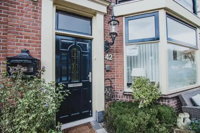 a brick house with a black door and windows at B&B de Zandtaart in Egmond aan Zee