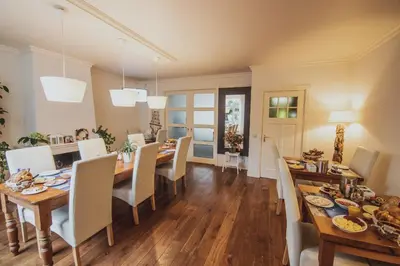 a dining room and living room with a table and chairs at B&B de Zandtaart in Egmond aan Zee