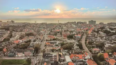 an aerial view of a city with the sun setting at B&B de Zandtaart in Egmond aan Zee