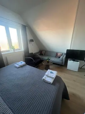 a bedroom with a bed and a living room at B&B de Zandtaart in Egmond aan Zee