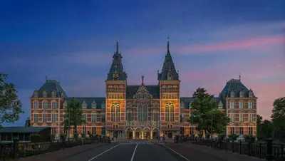 a large building with a sunset in the background at Mandarin Oriental Conservatorium, Amsterdam in Amsterdam