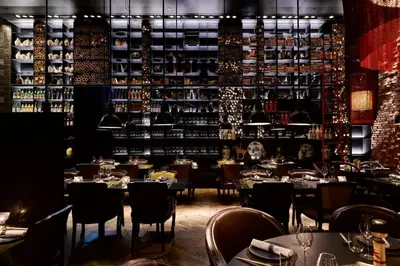 a restaurant with tables and chairs and a shelf with wine bottles at Mandarin Oriental Conservatorium, Amsterdam in Amsterdam
