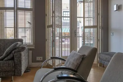 a living room with chairs and windows with blinds at Appartement Volendam in Volendam