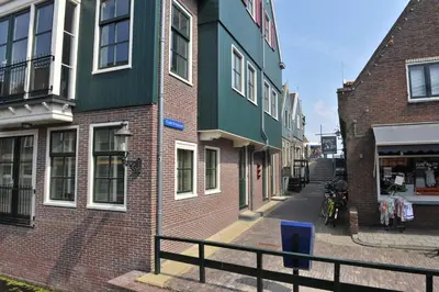 a narrow street with buildings and a motorcycle parked in front at Appartement Volendam in Volendam