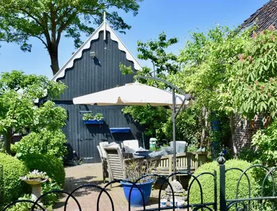 a patio with a table and chairs and an umbrella at Het Twiscker Huys in Twisk