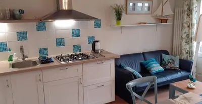 a kitchen with a blue couch and a kitchen with a stove at Close to the beach in Wijk aan Zee