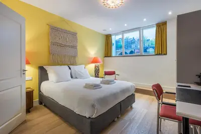 a bedroom with a bed and a desk and a window at The Old Lady in Amsterdam