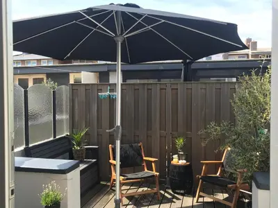a patio with two chairs and an umbrella at Pakhuis 5 in Katwijk aan Zee
