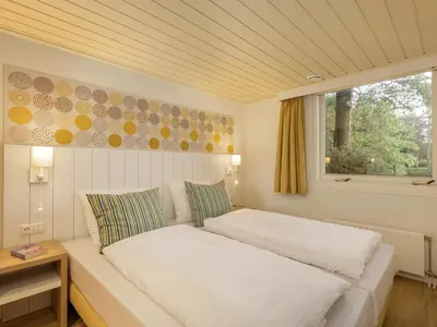 a white bed in a room with a window at Center Parcs De Eemhof in Zeewolde