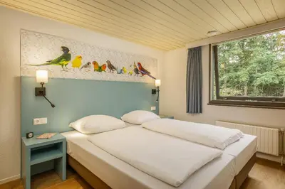 a bed in a bedroom with a picture of birds at Center Parcs De Eemhof in Zeewolde