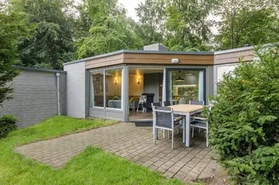 a small cottage with a table and chairs in a yard at Center Parcs De Eemhof in Zeewolde