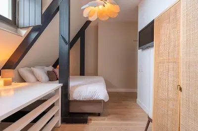 a small bedroom with a bed and a staircase at Hotel het Oude Raadhuis in Castricum
