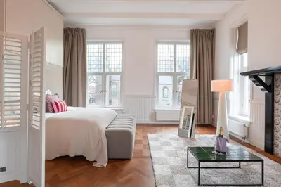 a white bedroom with a bed and a table at Hotel het Oude Raadhuis in Castricum