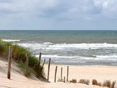a wooden fence on a beach next to the ocean at B&B de Petrakerk in Rijnsburg