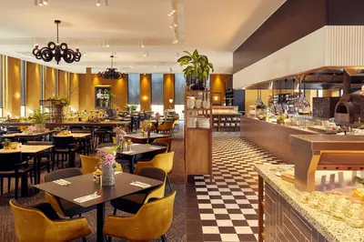 a restaurant with tables and chairs and a counter at Van der Valk Hotel Amsterdam - Amstel in Amsterdam