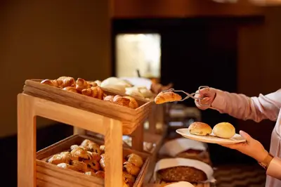 a person holding a plate of bread and pastries at Van der Valk Hotel Amsterdam - Amstel in Amsterdam