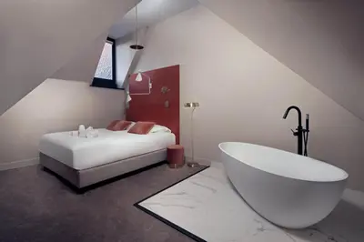 a bathroom with a white tub and a bed at The Anthony in Utrecht