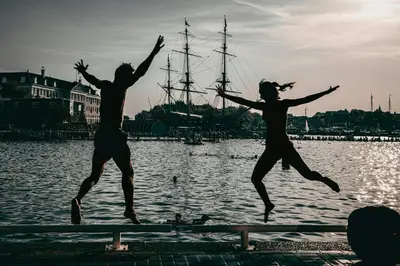 two people jumping in the air in front of the water at Studio Eelhouse in Amsterdam