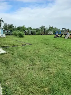 a large grassy field with a playground in the background at Bed & Breakfast ARKEN AE in Zuiderwoude