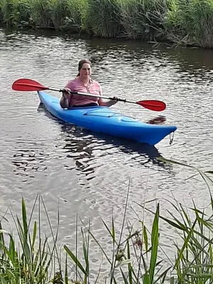 a woman in a blue kayak on the water at Bed & Breakfast ARKEN AE in Zuiderwoude