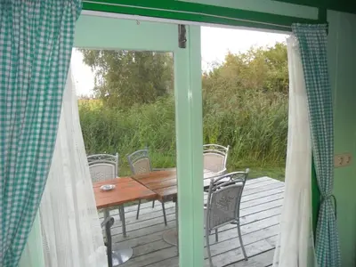a screened in porch with a wooden table and chairs at Bed & Breakfast ARKEN AE in Zuiderwoude